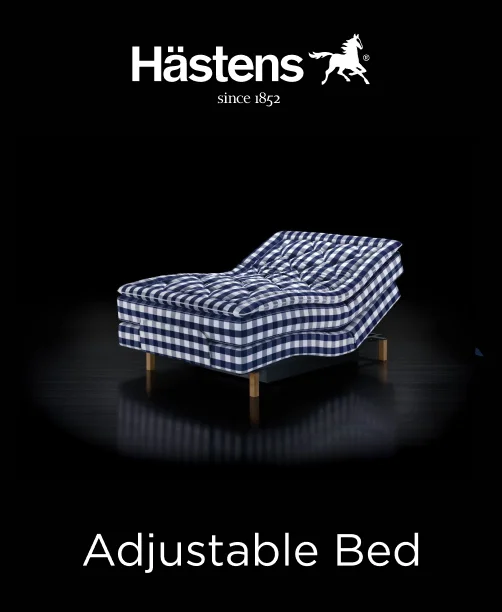 Hastens adjustable bed with upholstered gray base and signature blue-check design on the integrated mattress